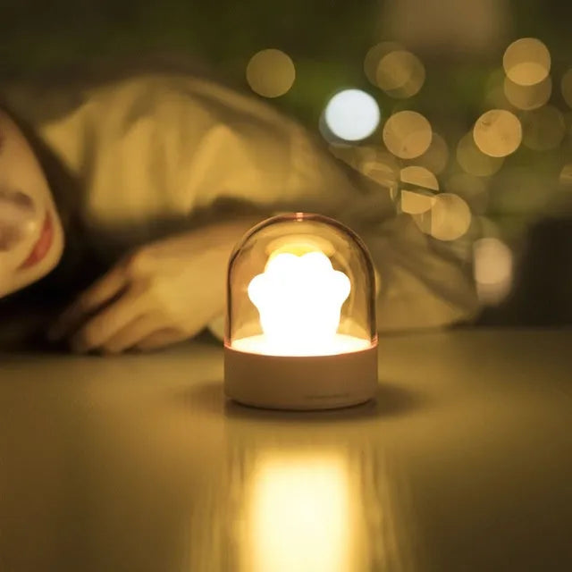 Grey cat paw shaped musical night light with USB charging cable on wooden desktop