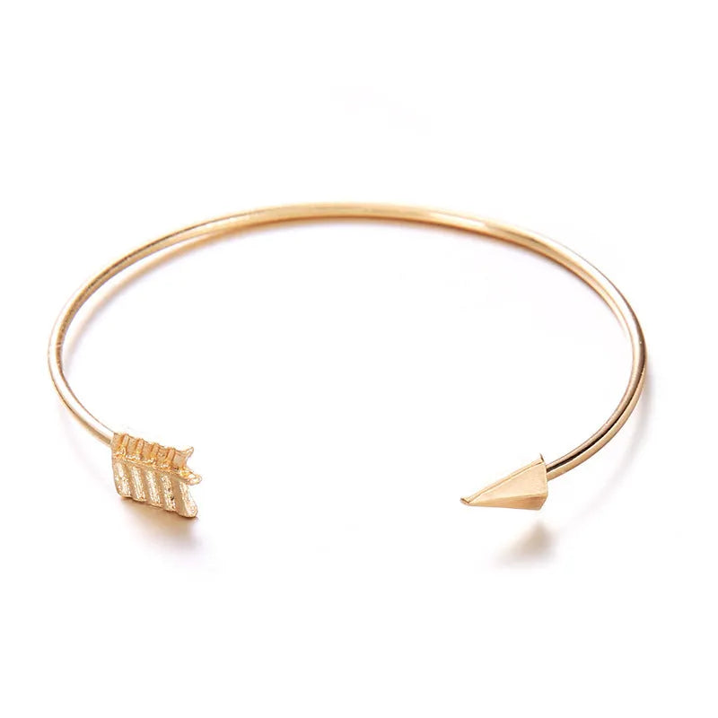 Gold-coloured women's vintage cuff bracelet with an arrow and knotted design motif.