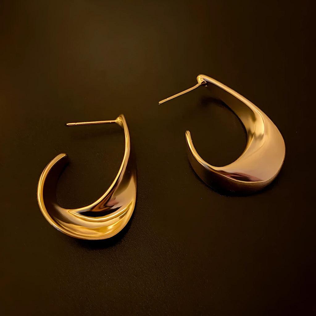 Geometric twisted metal earrings with electroplated gold or silver finish and round design elements