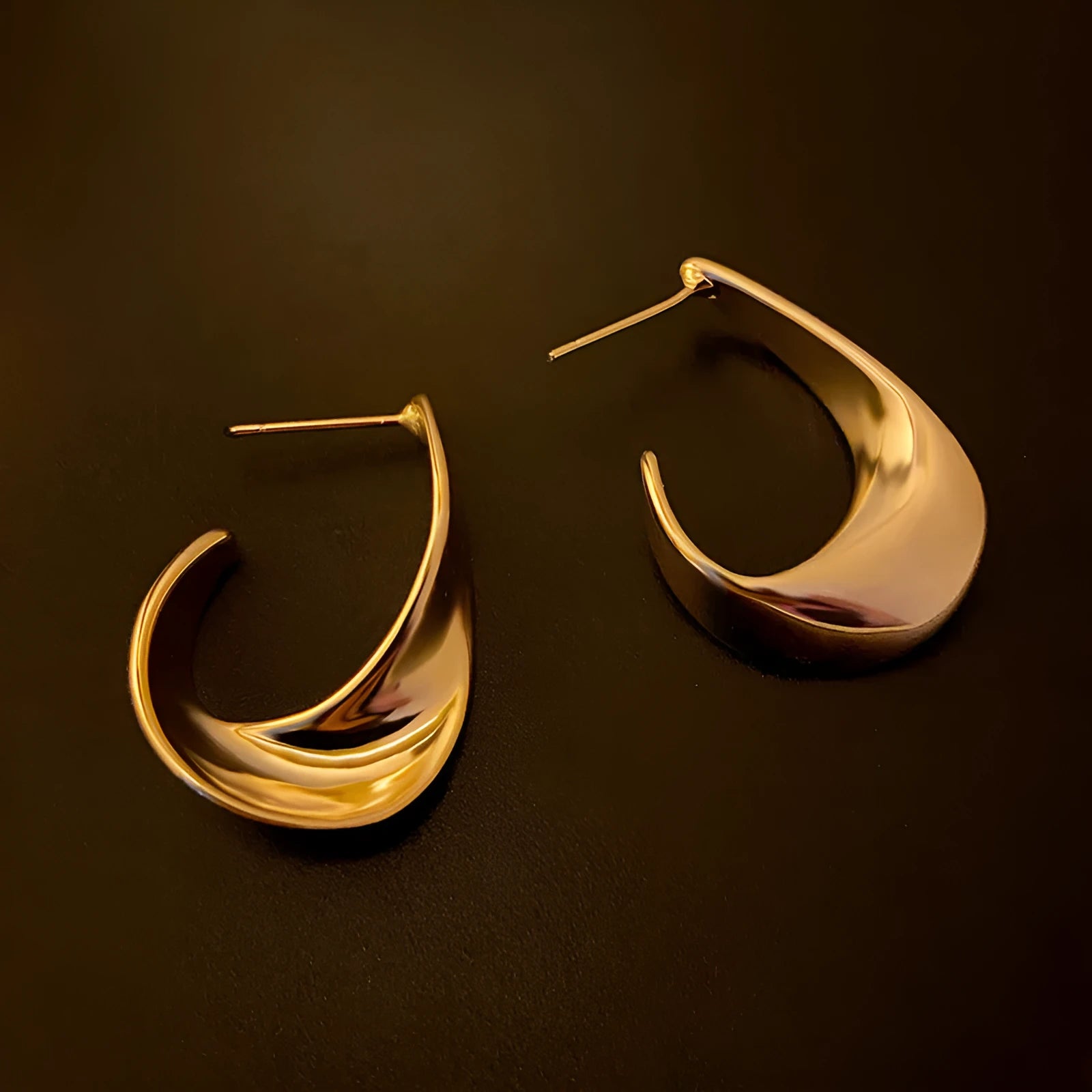 Geometric twisted metal earrings with electroplated gold or silver finish and round design elements