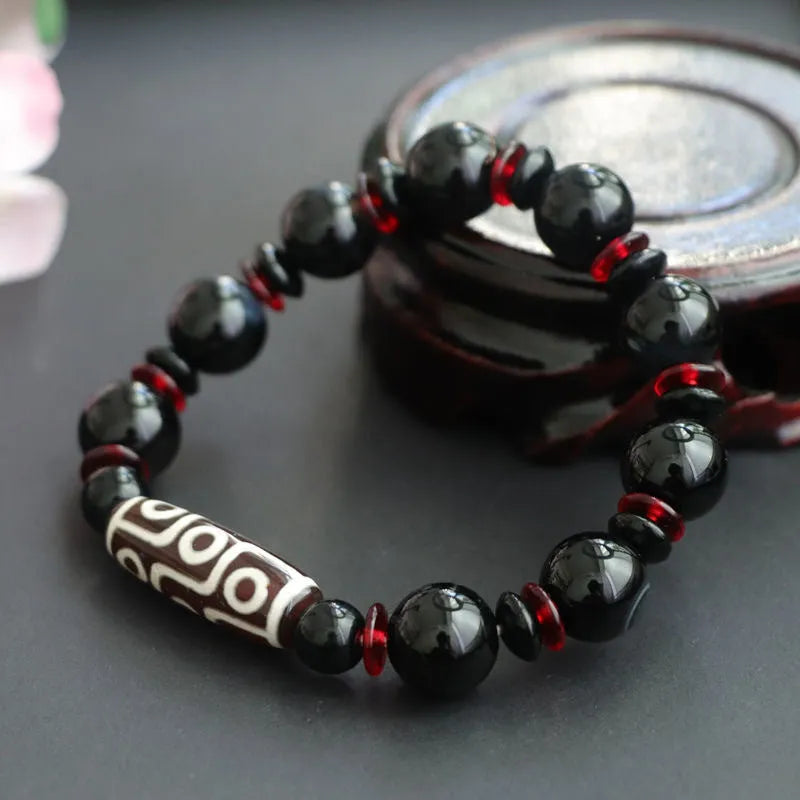 Hand-woven black agate Dzi bead bracelet with 11mm geometric beads on a wrist