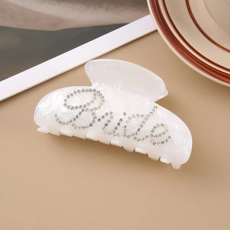 Acrylic hair barrette with diamond pattern and English letters measuring 10cm wide in pink colour