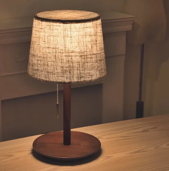 Walnut-coloured solid wood bedside lamp with white cloth shade and cable switch