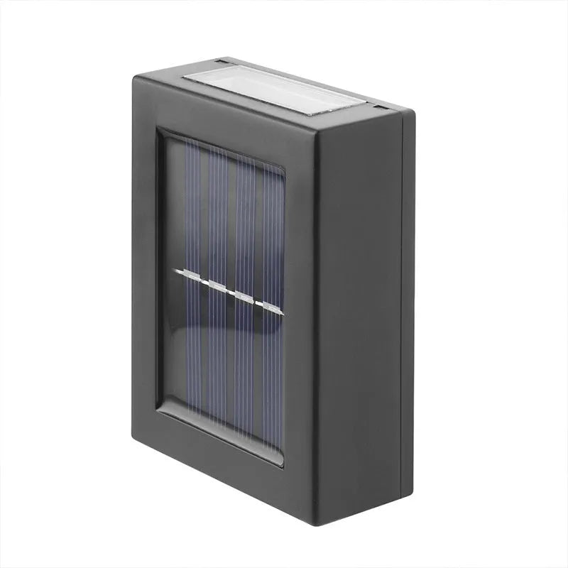Small solar-powered black plastic outdoor wall light with LED up and down irradiation on a garden wall
