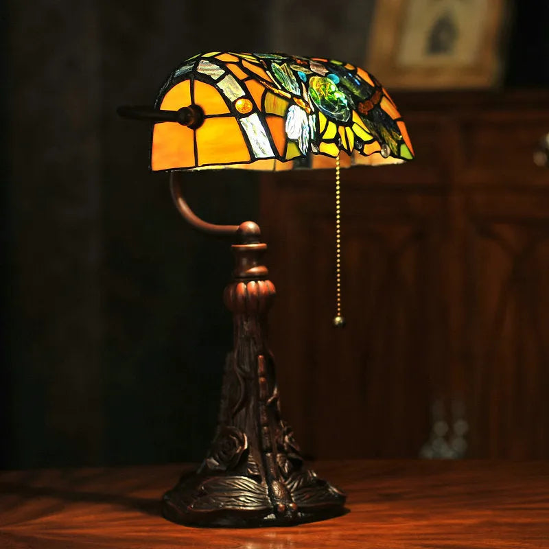 10-inch Tiffany table lamp with coloured glass shade and resin base on a desk.
