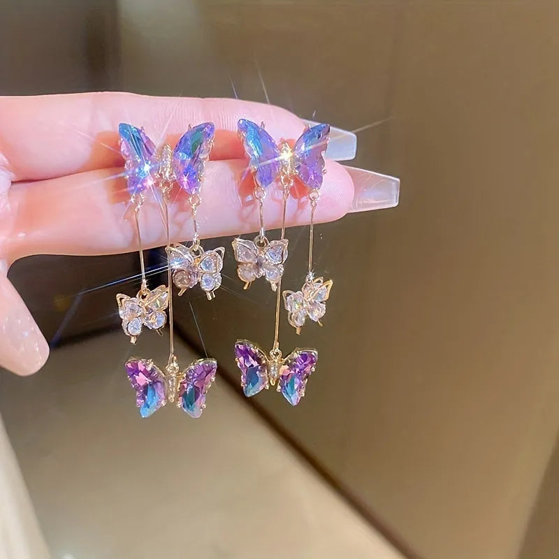 Close-up of women's silver needle blue purple butterfly alloy earrings with crystal flowers and a dangle tassel.