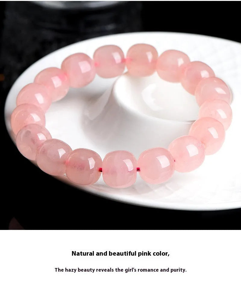 Pink natural crystal bracelet with polished geometric barrel-shaped beads on a wrist.