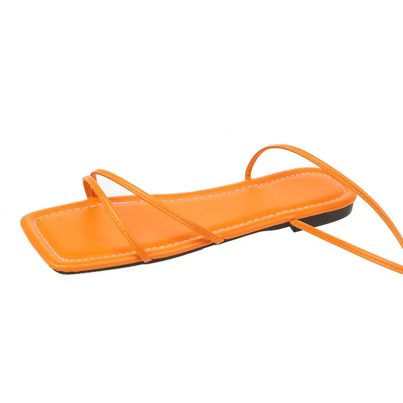 Women's flat sandals with ankle bandage detail and square toe in black, white, or orange.