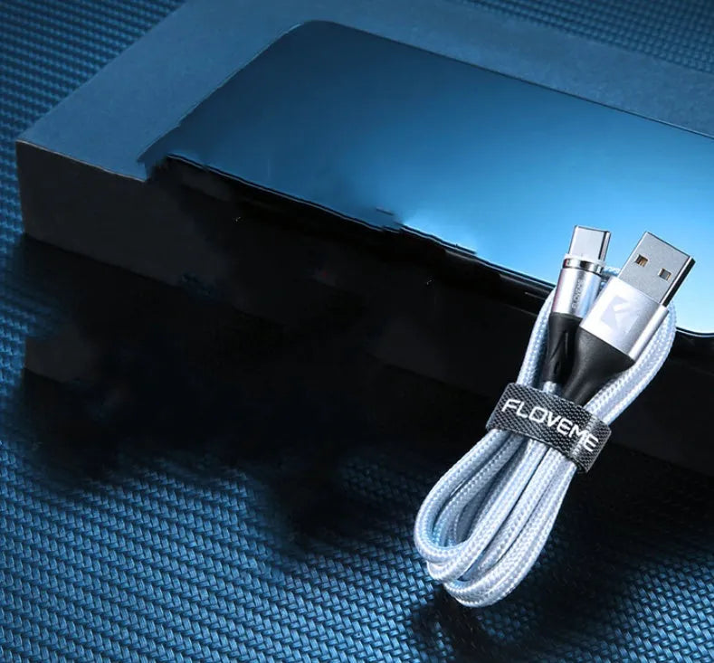 Black magnetic data cable with USB-C connector and side LED light, laid flat next to its aluminium foil packaging.