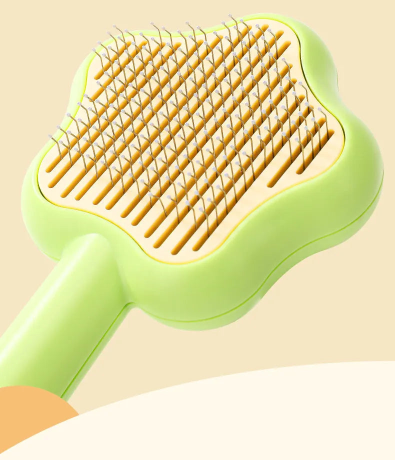 Green handled self-cleaning pet comb with stainless steel teeth on a white background.