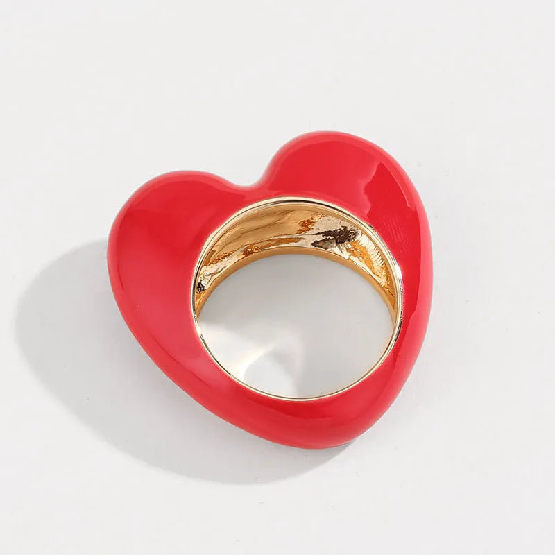 Three-dimensional heart-shaped enamel fashion ring in red, shown from the side.