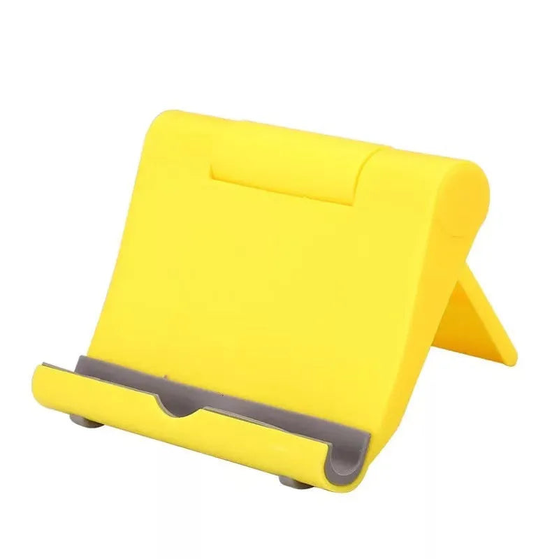 Black PE plastic folding phone stand holding a mobile phone at an angle on a wooden desk.