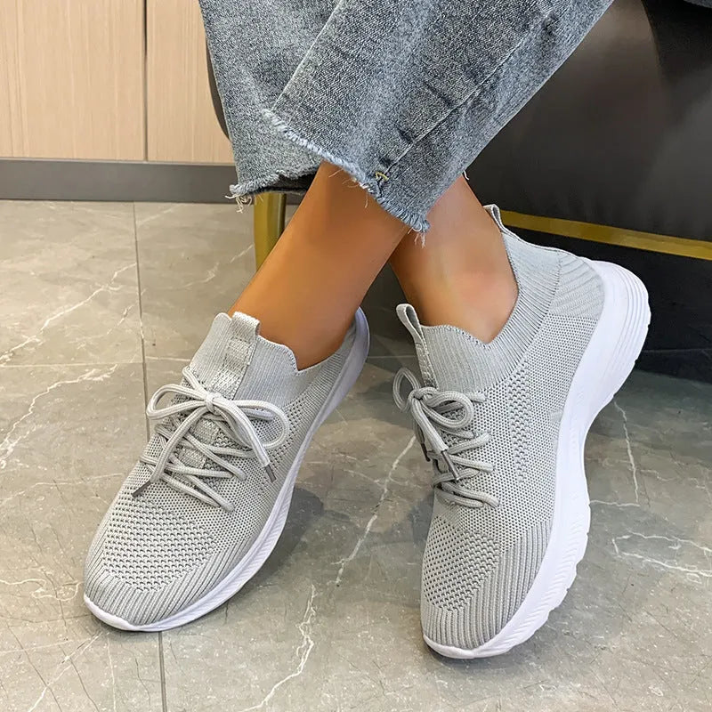 Women's low-top running shoes in creamy white with Flyknit upper and flat rubber sole.