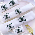 Set of six black metal spider-shaped napkin rings for Halloween table decoration.