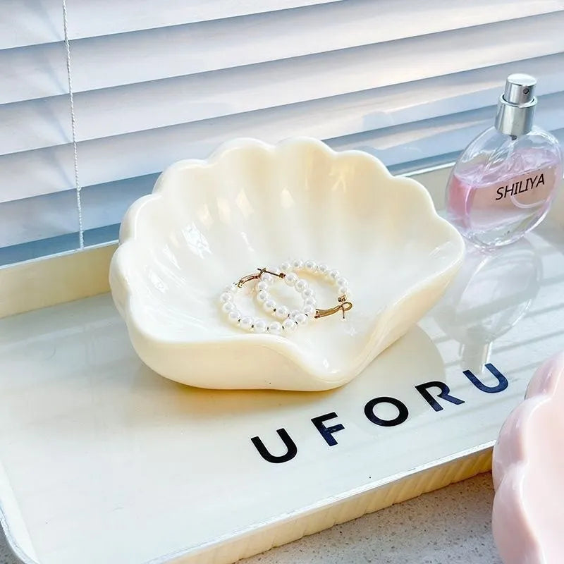 Pearl white plastic shell-shaped soap dish with drainage channels measuring 12cm long