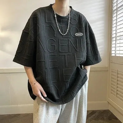 Men's grey loose-fit t-shirt with a raised 3D letter print on the front.