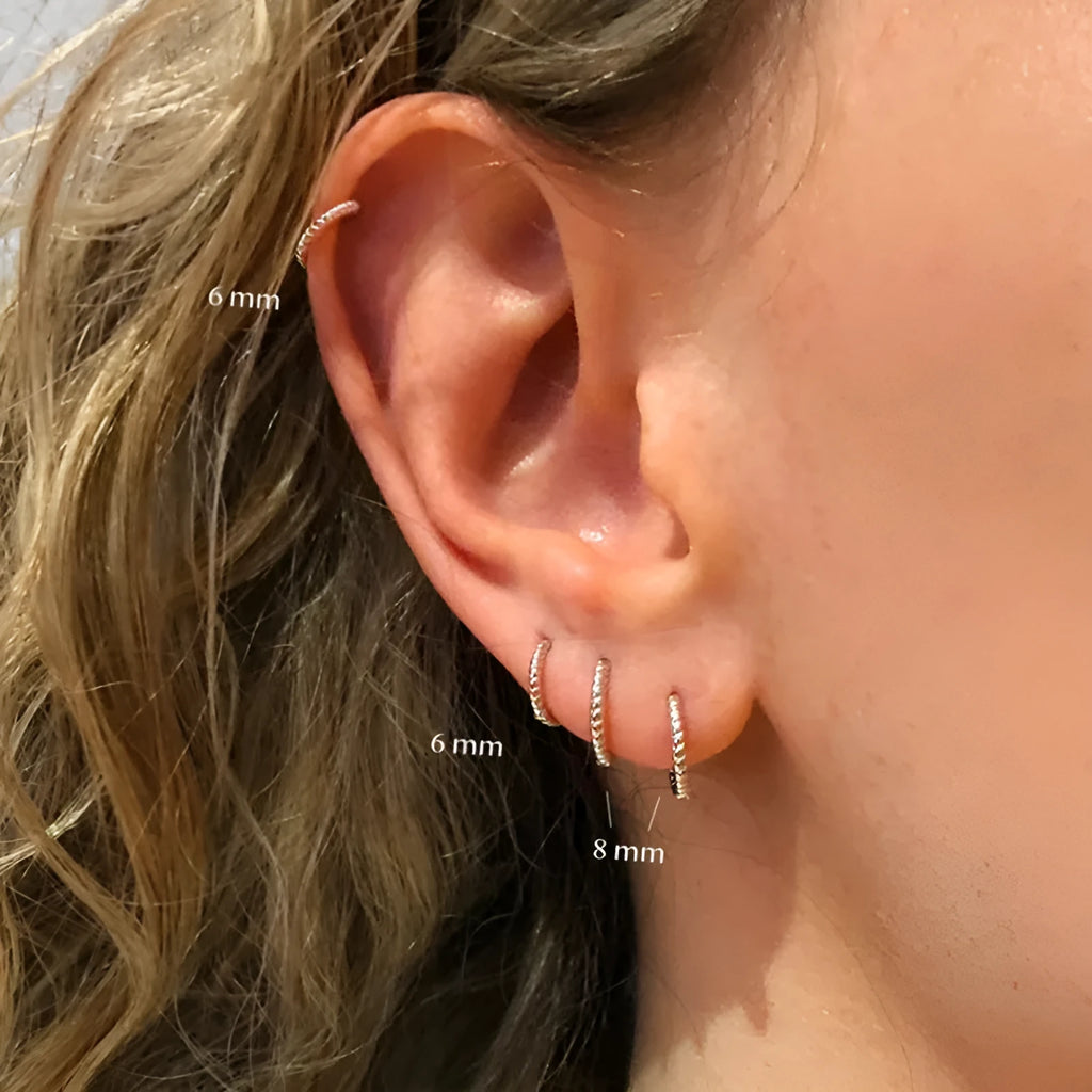 Close-up of twisted sterling silver hoop earrings showing the textured string design.