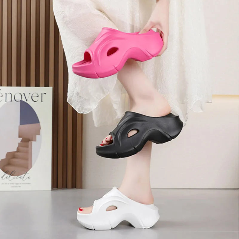 Women's white thick-soled EVA slippers with round toe on a sandy beach.