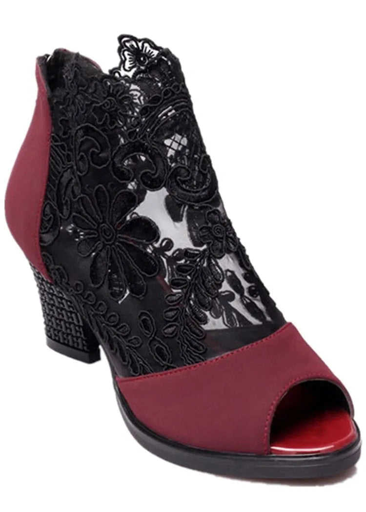 Black lace gladiator sandals with a square high heel, floral detail, and a zip closure at the ankle.