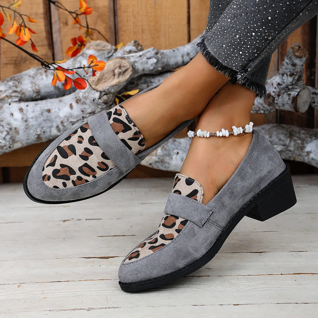 Women's leopard print suede slip-on shoe with a chunky mid heel and pointed toe on a brown background.
