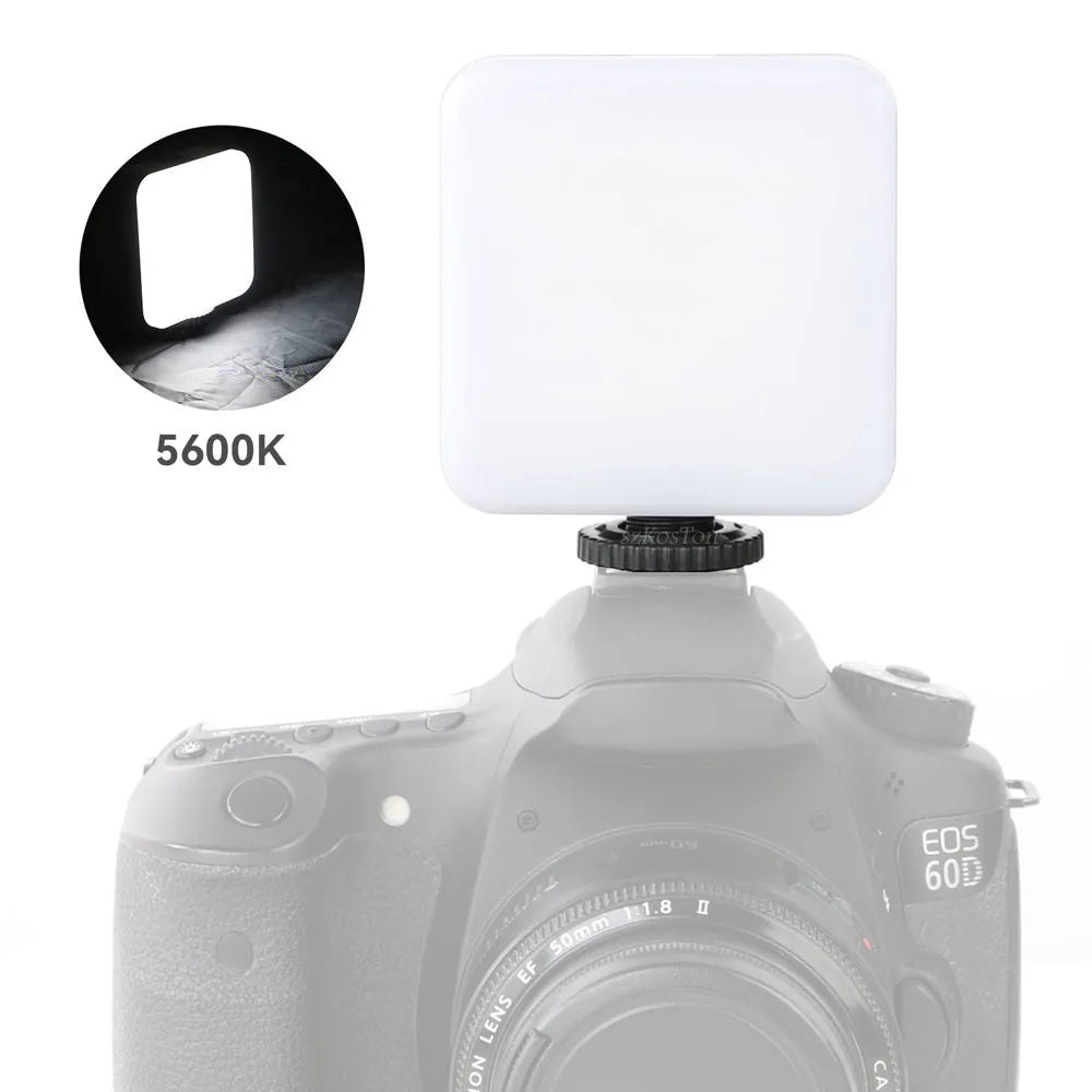 Square-shaped mini LED camera flash with hot shoe mount on a small tripod stand.