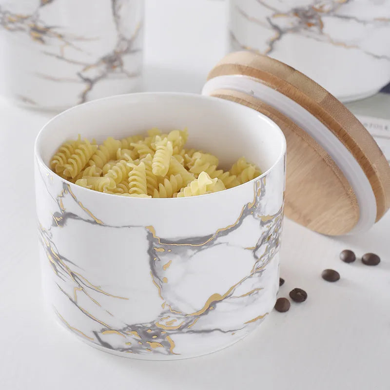 Three marbled ceramic jars with bamboo lids in large, medium and small sizes on a kitchen counter
