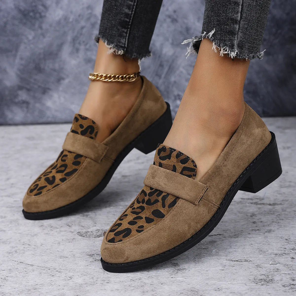 Women's leopard print suede slip-on shoe with a chunky mid heel and pointed toe on a brown background.