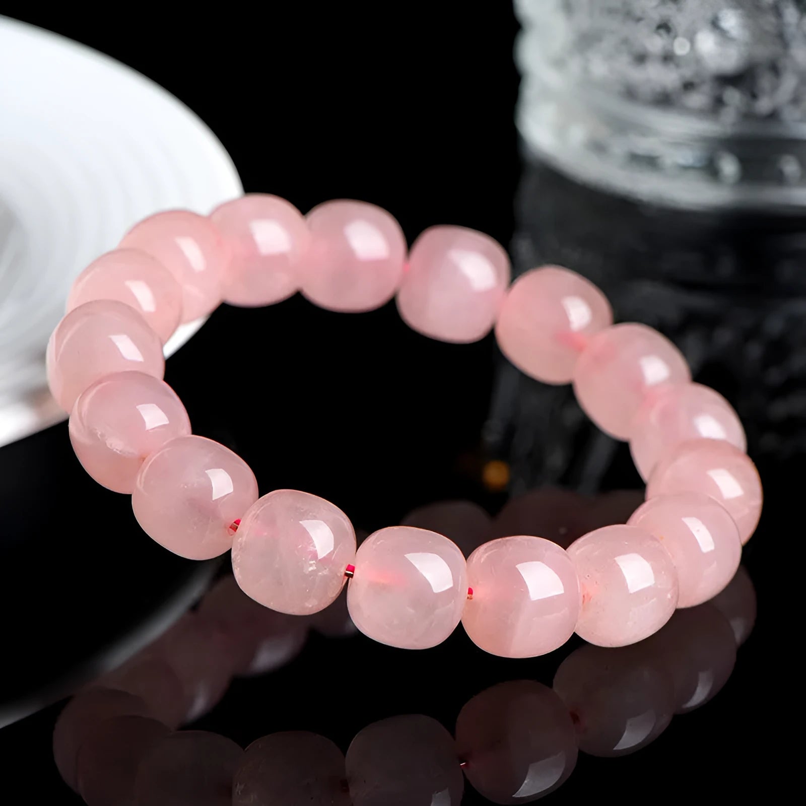 Pink natural crystal bracelet with polished geometric barrel-shaped beads on a wrist.