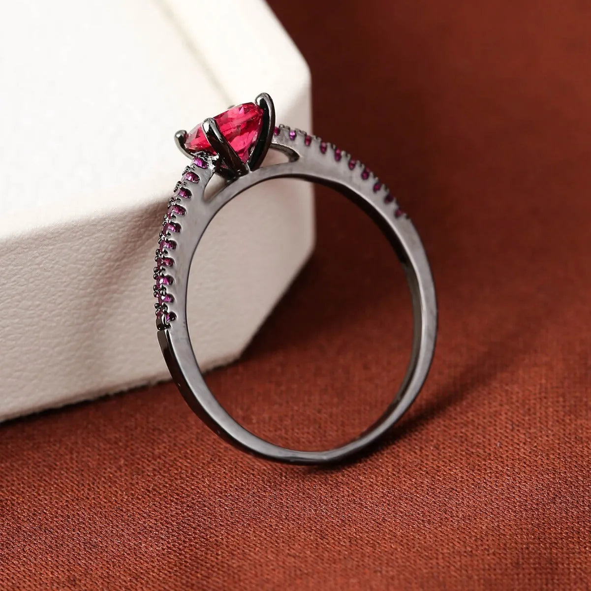Geometric hexagon design copper zircon ring in various electroplated colours on a size guide.