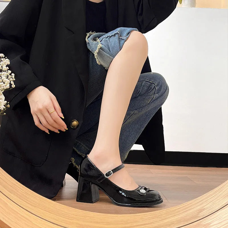Women's black patent leather chunky heel shoes with round toe and buckle.