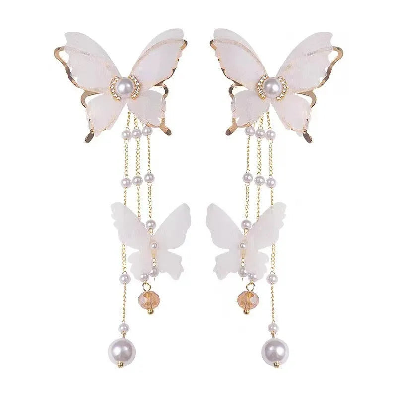 White butterfly earrings with lace pattern wings, pearl and rhinestone details, and dangling tassels