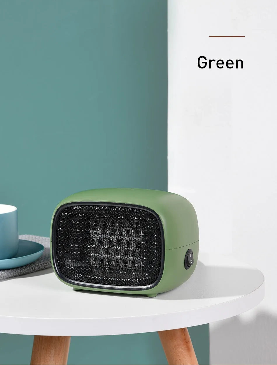 Mini green PTC ceramic fan heater on a desk showing compact size
