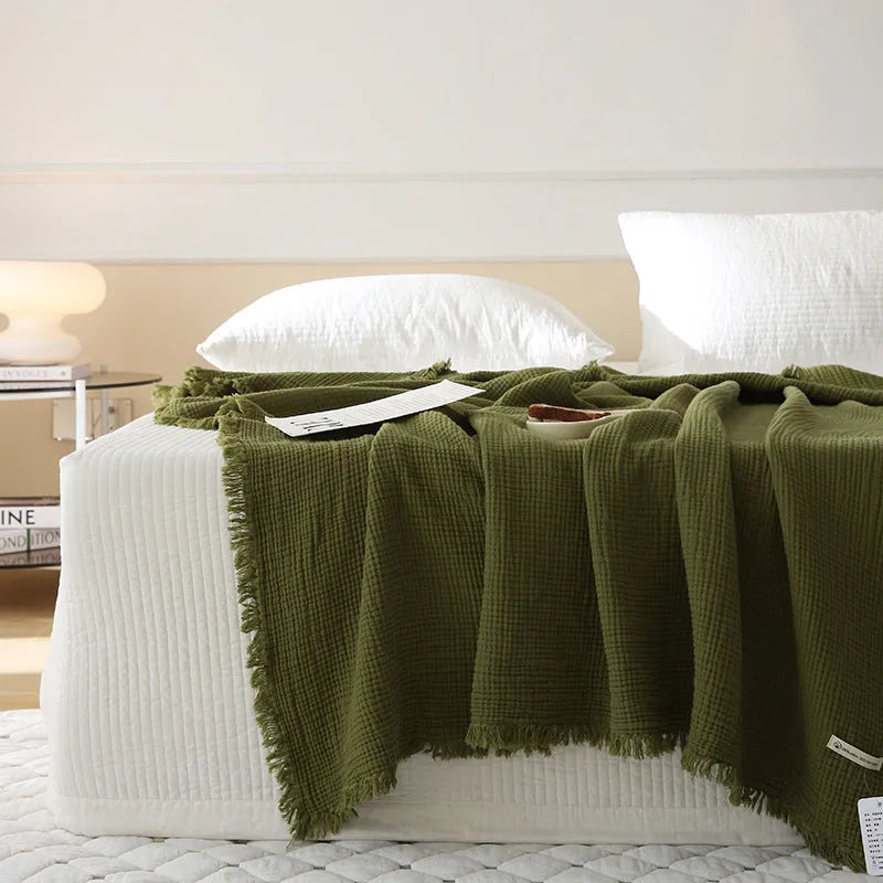 Four-layer gauze cotton blanket with tassel trim in navy blue colour laid flat