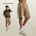 Man's loose-fit cotton terry shorts in a batik wash colour with a craft patch detail, shown in a street fashion style.