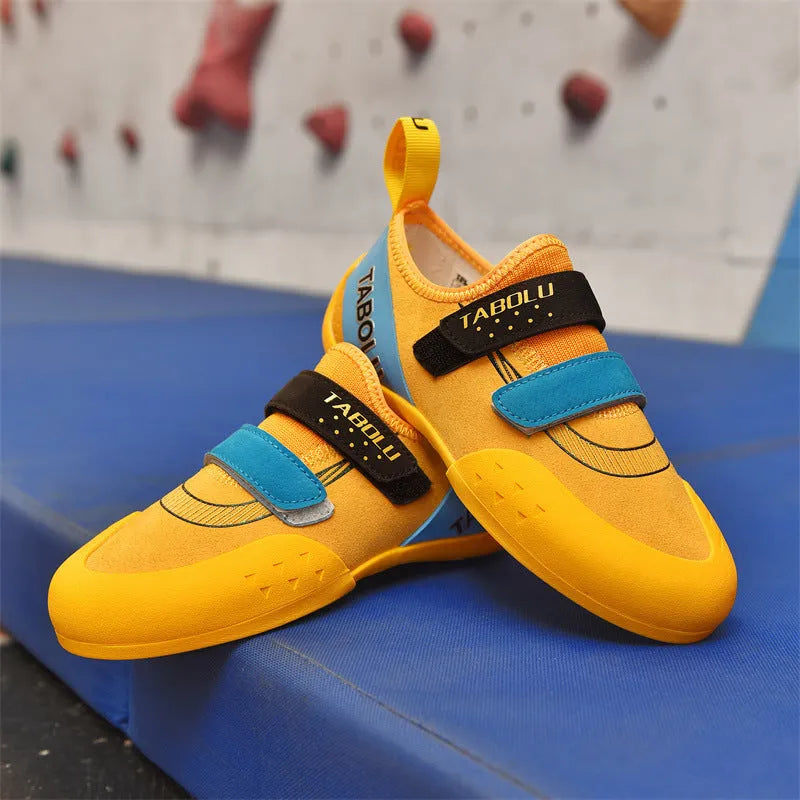 A pair of beginner rock climbing shoes with a velcro strap, shown in a black and red colour combination.