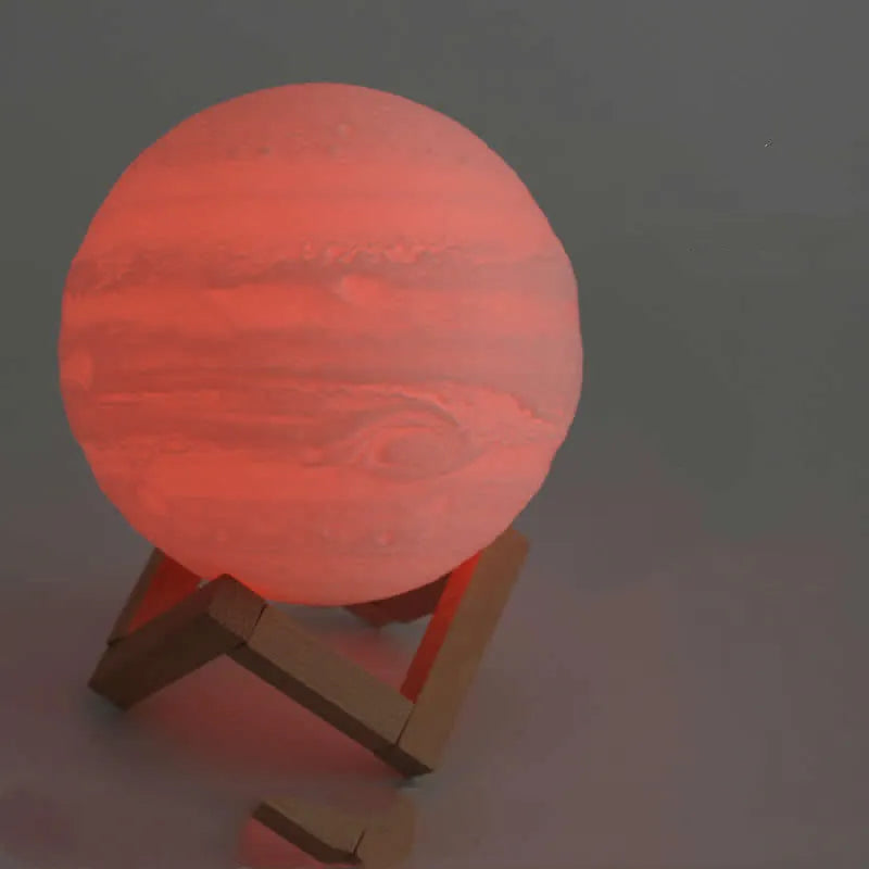 3D printed white moon lamp on a wooden stand with a glowing centre.