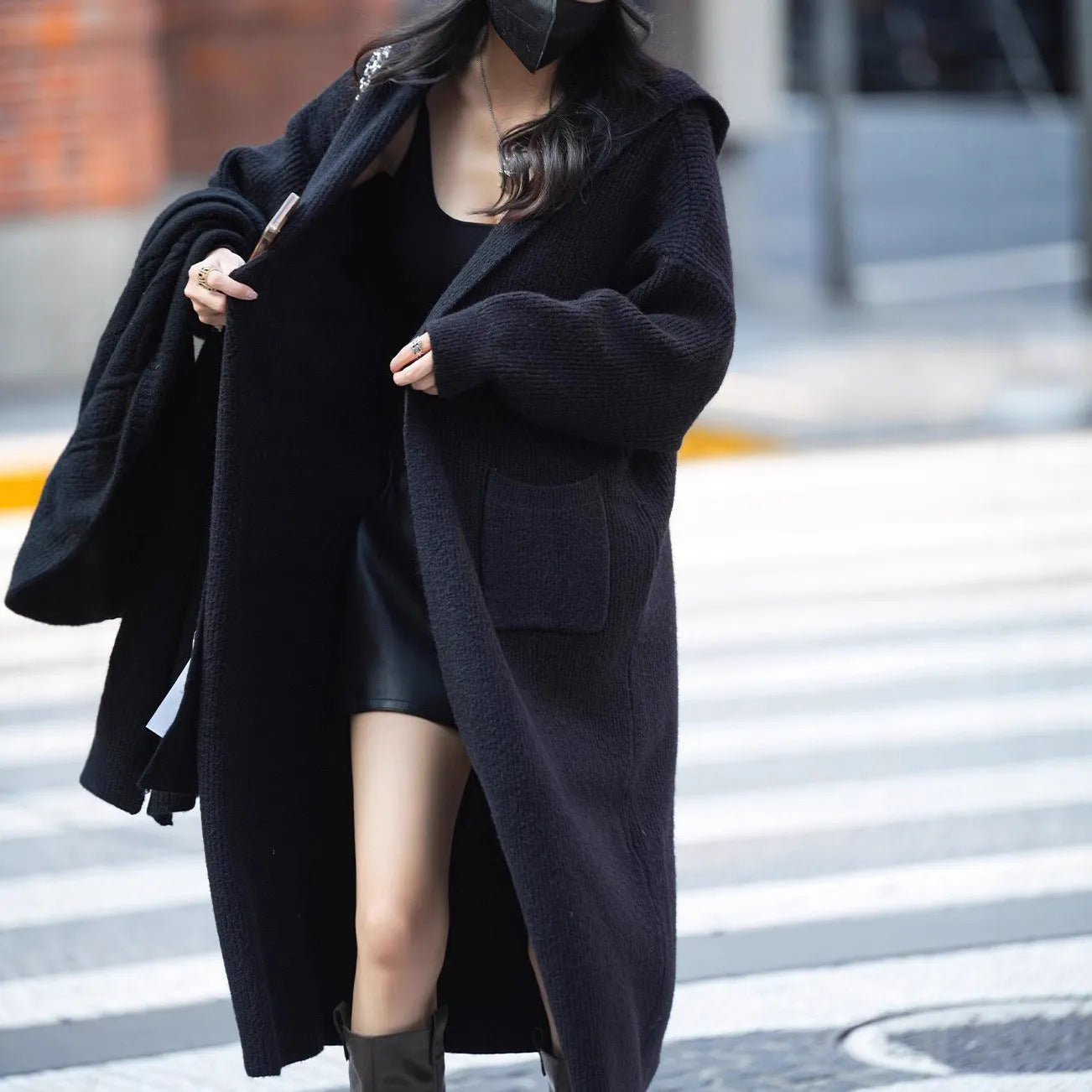 Long grey knitted cardigan coat with a hood, shown in a loose fit.