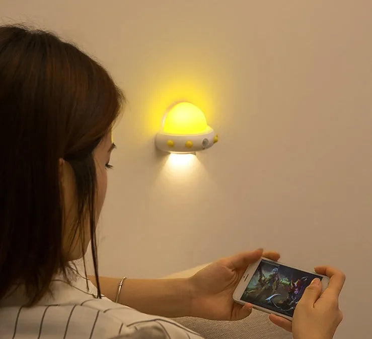 Remote control UFO-shaped bedside night light in blue, pink, or white colours.