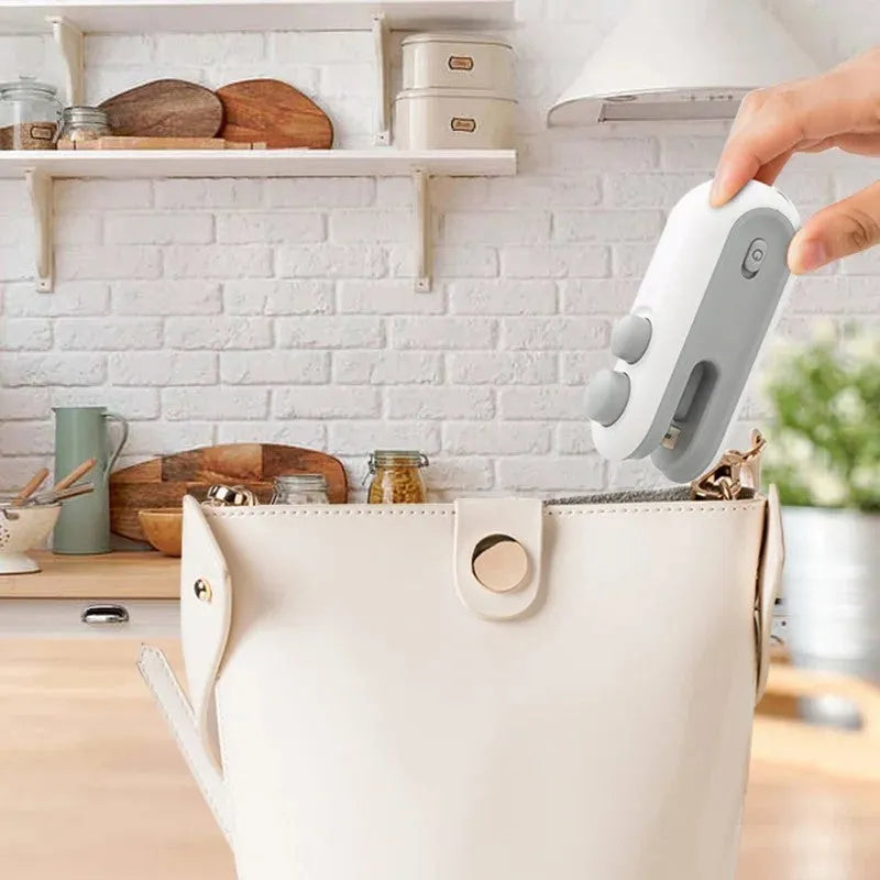 White handheld USB rechargeable heat sealer with cutter blade on a kitchen counter