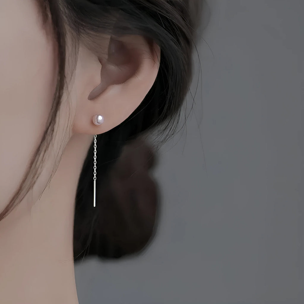 Sterling silver ear string with assorted small geometric and pearl charms on an alloy ear wire.