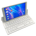 Black and white views of a folded mini wireless Bluetooth keyboard for tablets next to a smartphone.