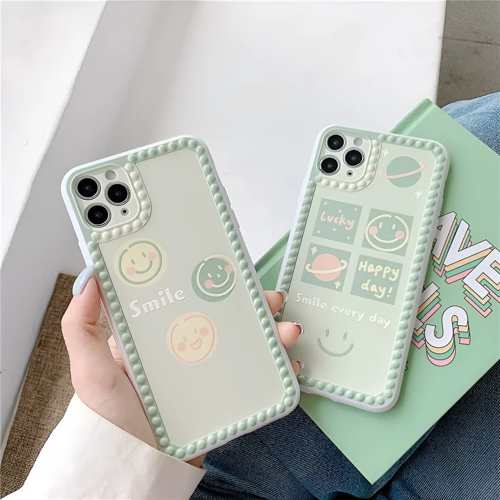 Green TPU iPhone case with geometric smiley face and polka dot design on a table.