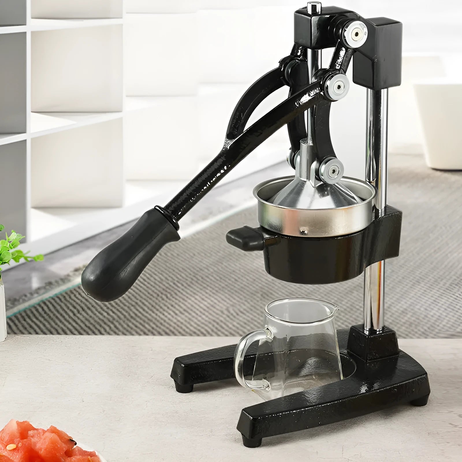 Tall black manual citrus juicer with cast iron base and stainless steel cone on a kitchen counter.