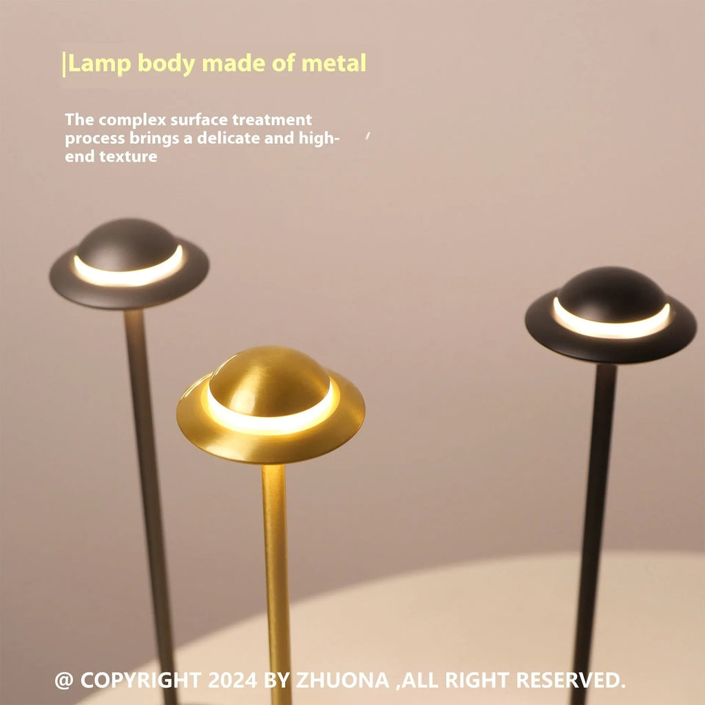 Modern black UFO-shaped rechargeable table lamp with touch-sensitive dimming controls on a wooden desk.