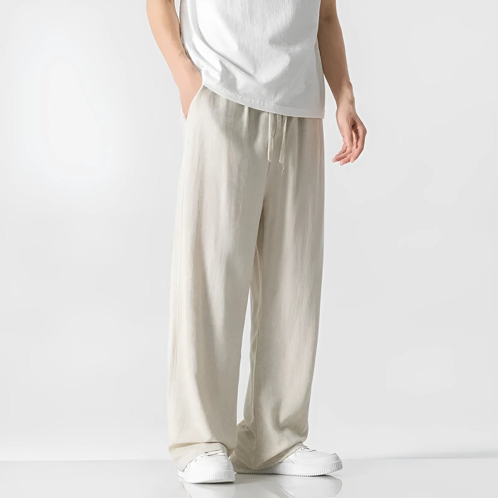 Men's beige loose straight-leg linen trousers with a drawstring waist on a neutral background.