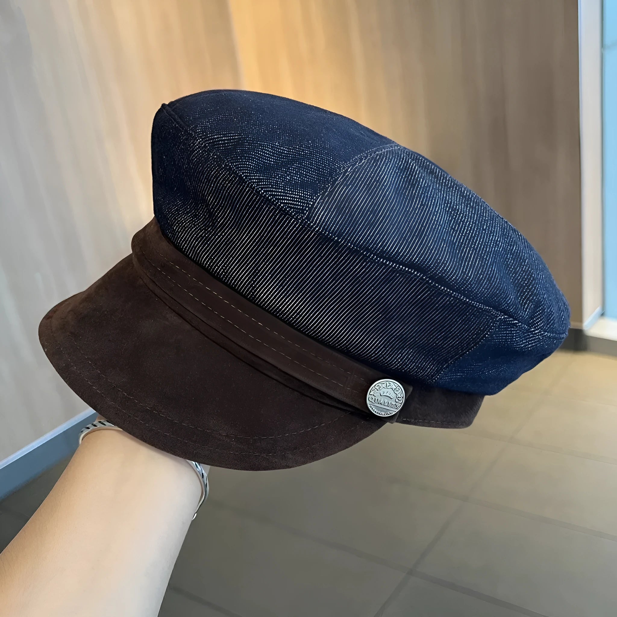 Adjustable octagonal denim newsboy hat in dark blue with contrast brim on white background