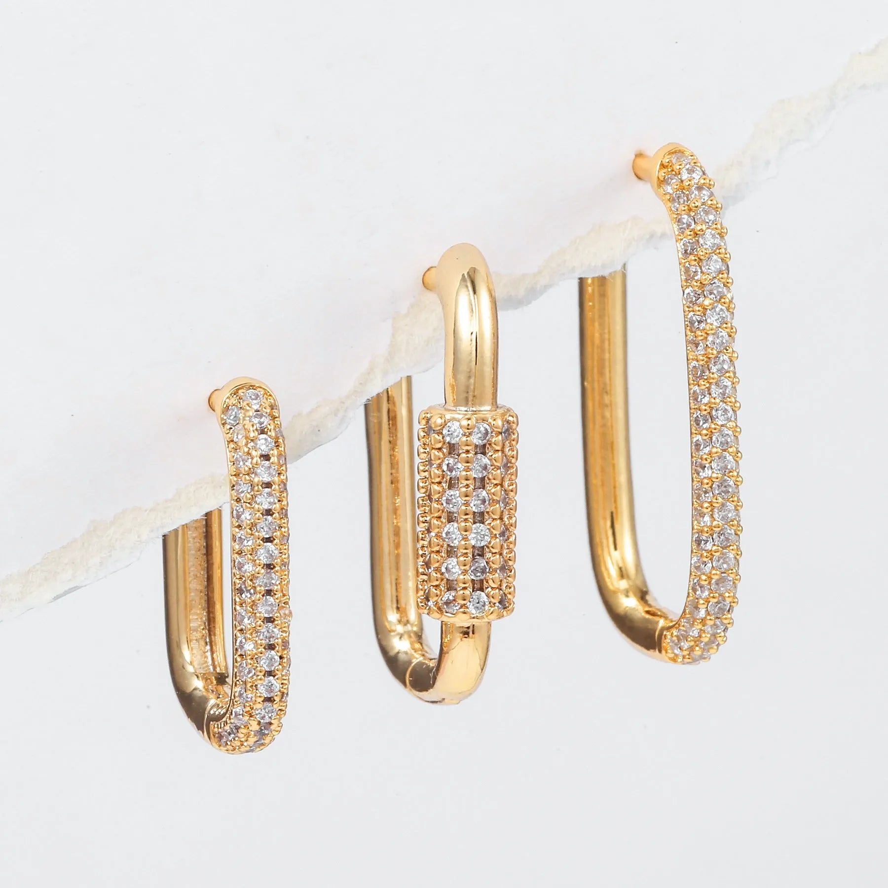 Three geometric ear clips with micro inlaid zircon detailing on copper in gold and white colours