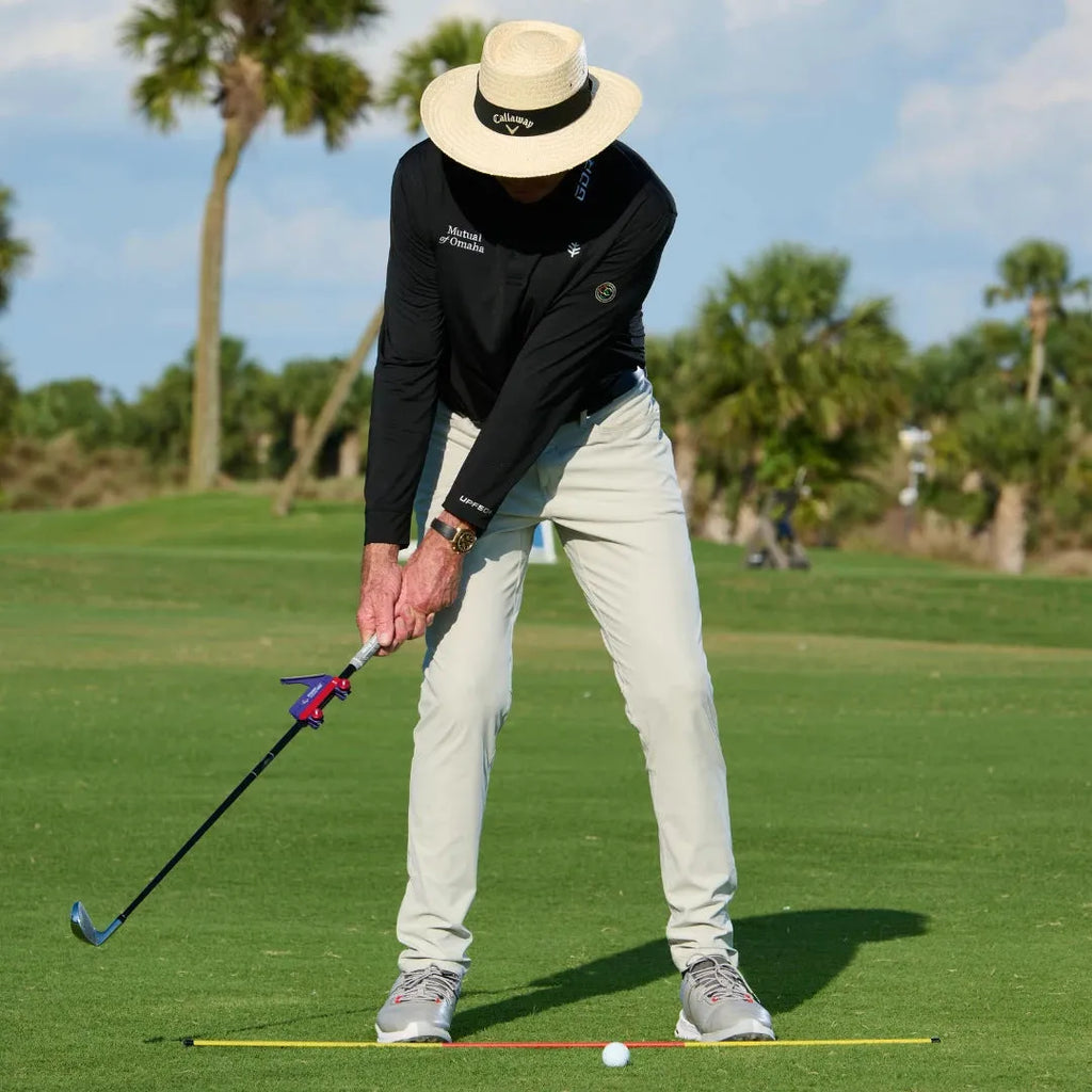 Plastic golf swing plane training aid simulator on a green background.