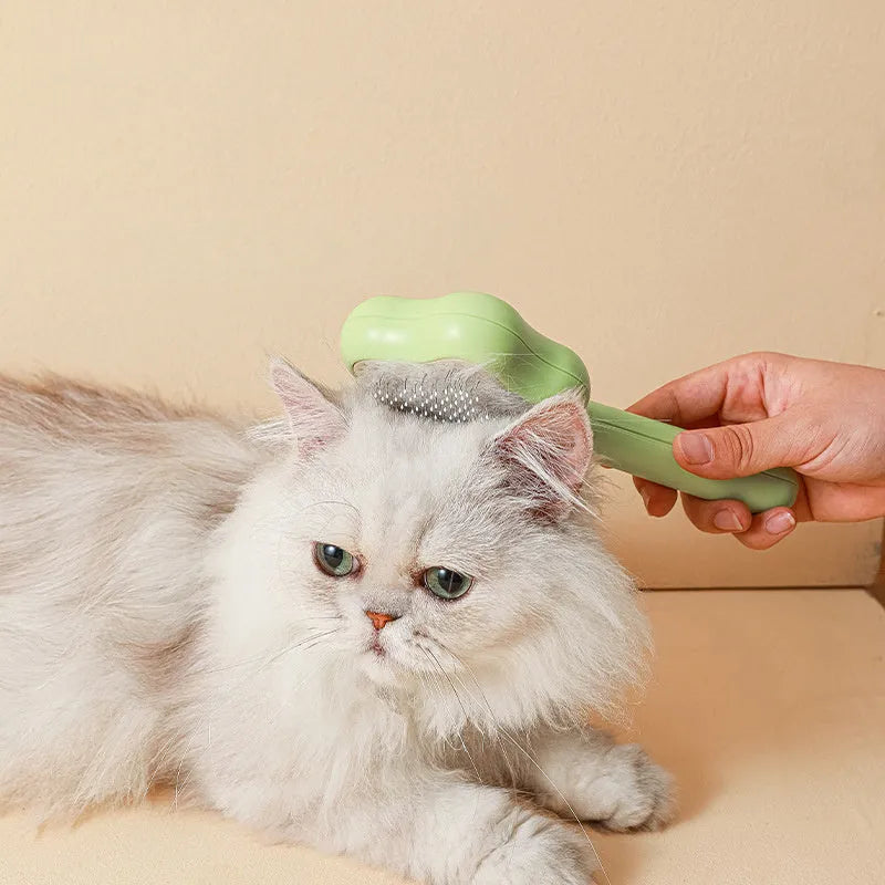 Green handled self-cleaning pet comb with stainless steel teeth on a white background.