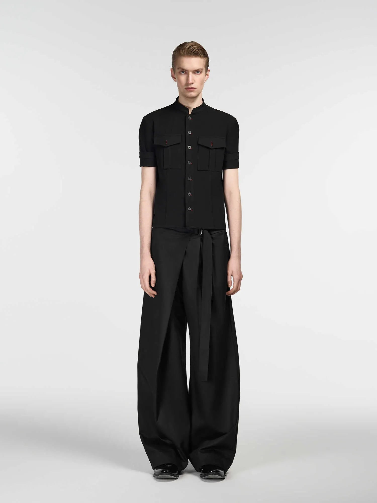 Black straight-leg trousers with single pleat front and adjustable waistband on hanger